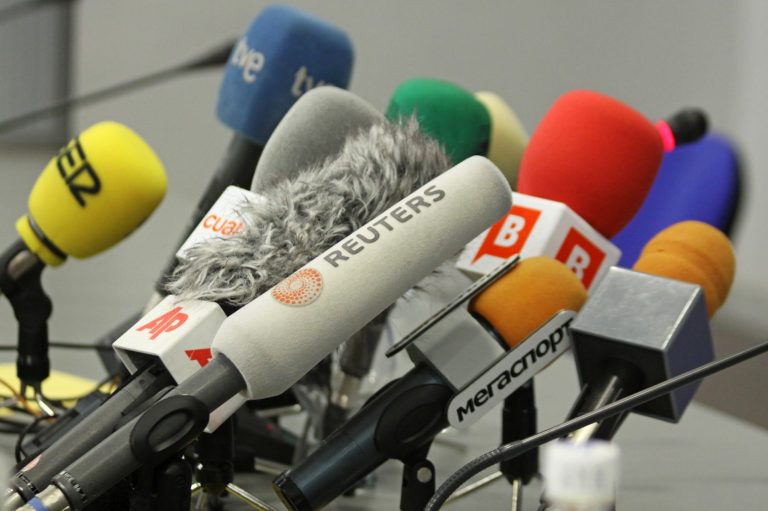 An array of microphones arranged for a press conference.